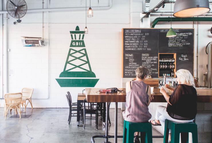 昆士蘭州佛特谷Green Beacon Brewing Co.的鄉村式工業風時尚場地內兩人坐在綠色酒吧凳上©Anwyn Howarth