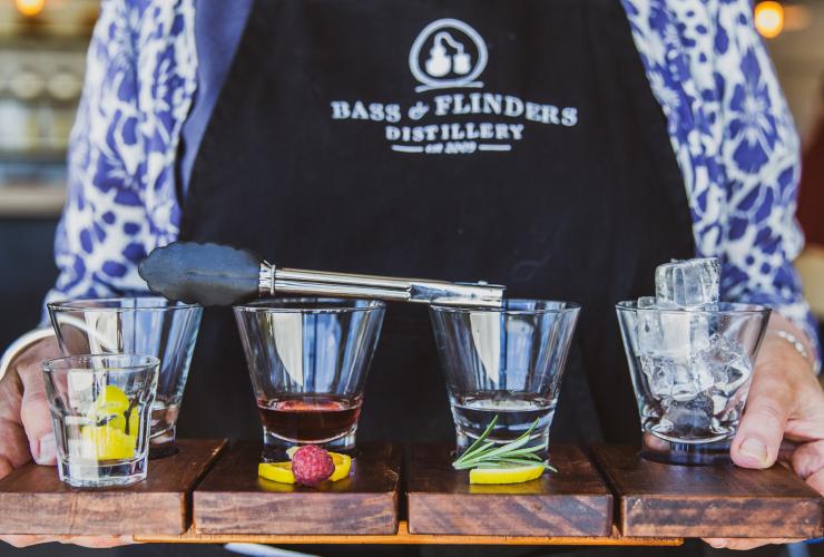 維多利亞州摩寧頓半島Bass & Flinders釀酒廠內調酒師拿著有四杯不同烈酒的托盤，杯前放了些配料©澳洲旅遊局
