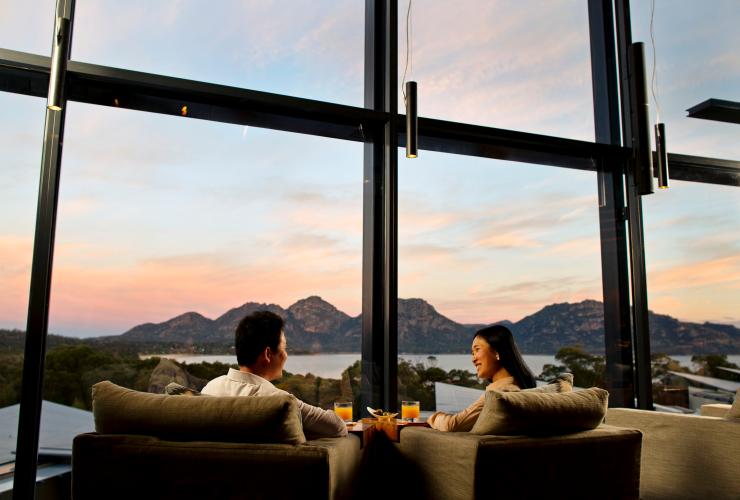 塔斯曼尼亞Saffire Freycinet一對情侶坐在沙發上欣賞歌斯灣黃昏的山水景致©Myka Photography